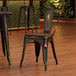 A Lancaster Table & Seating distressed copper metal chair with a walnut wood seat at a table in a restaurant.