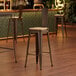 A Lancaster Table & Seating copper barstool with a natural wood seat at a wooden table in a bar