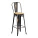 A black metal Lancaster Table & Seating bar stool with a natural wood seat.