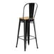 A Lancaster Table & Seating black metal bar stool with a natural wood seat.