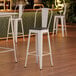 A white Lancaster Table & Seating barstool with a black wood seat