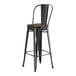 A black metal Lancaster Table & Seating barstool with a walnut wood seat.