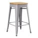 A Lancaster Table & Seating gray metal counter height stool with a natural wood seat.