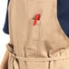 A man wearing a khaki Uncommon Chef bib apron with 3 pockets.