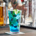 A close-up of a blueberry limeade in an Acopa Select stackable cooler/mixing glass with limes and ice.