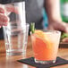 A person pouring a drink into an Acopa Select stackable rocks glass with a slice of orange on the rim.