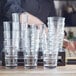 A woman stacking Acopa Select rocks glasses on a table.