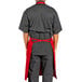 A man wearing a black shirt and red Uncommon Chef bib apron with 3 pockets.