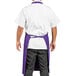 A man wearing a purple Uncommon Chef bib apron with 3 pockets.