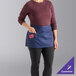 A navy blue customizable waist apron with three pockets, worn by a person.