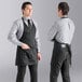 Two men wearing black Uncommon Chef tuxedo aprons standing in a professional kitchen.
