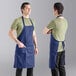 Two men wearing navy blue Uncommon Chef bib aprons.