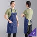 A man wearing a navy blue Uncommon Chef bib apron.