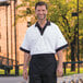 A man wearing a white shirt and a black Uncommon Chef waist apron with three pockets.