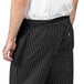 A person wearing a black Uncommon Chef waist apron with three pockets.
