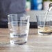 A person pouring liquid into two stackable Acopa Select rocks glasses.