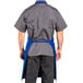 A man wearing a royal blue Uncommon Chef bib apron.
