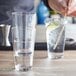 A person mixing a drink with a straw in an Acopa Select stackable beverage glass.