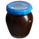 A Dalmatia Plum Spread jar with a blue lid on a table in a deli.