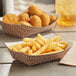 A bowl of french fries and chicken nuggets on a Carnival King paper food tray.