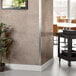 A stainless steel Regency wall corner guard installed in a room with a plant in a pot.