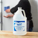 A man using a Kutol Health Guard gallon of alcohol sanitizer on a counter.