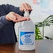 A hand using a pump to dispense Kutol Health Guard hand sanitizer from a plastic jug.