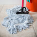 A Carlisle blue and white wet mop on a tile floor.