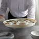 A waiter holding a white plastic serving tray of oysters on ice.