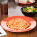 A bowl of salad with vegetables and a plate of spaghetti on a table.