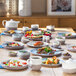 A table with Luzerne white porcelain deep plates filled with food.