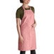 A woman wearing a mauve Intedge bib apron with 2 pockets.