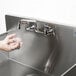 A person washing their hands in an Advance Tabco stainless steel commercial sink.