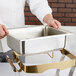 A person holding a stainless steel water pan.
