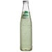 A close up of a Sidral Mundet green apple soda glass bottle with liquid and label.