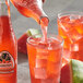 A person pouring Jarritos Watermelon soda into a glass with ice.