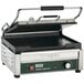 A Waring Tostato Supremo panini grill with a green and black handle.