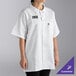 A woman wearing a white Uncommon Chef cook shirt with a black and white logo.