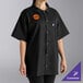 A woman wearing a black Uncommon Chef cook shirt with orange buttons.