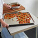 A chef using a Vollrath Wear-Ever bun pan to prepare food.