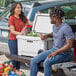 A man and woman standing in the back of a truck with a CaterGator cooler.