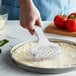 A hand using an American Metalcraft dough docker to make pizza.