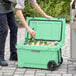 A man putting bottles in a CaterGator Seafoam outdoor cooler.
