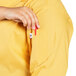 A person putting a red and white tag on the pocket of a sunflower print chef coat.