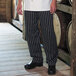 A person wearing Uncommon Chef black and white striped chef pants.
