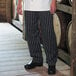 A person wearing Uncommon Chef black and white striped chef pants.