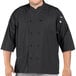 A man wearing an Uncommon Chef black 3/4 sleeve chef coat with side vents.