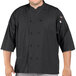A man wearing a black Uncommon Chef 3/4 sleeve chef coat with side vents.