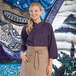 A woman wearing a Uncommon Chef eggplant 3/4 length sleeve chef coat.
