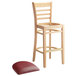 A Lancaster Table & Seating wooden ladder back bar stool with a burgundy vinyl seat detached.